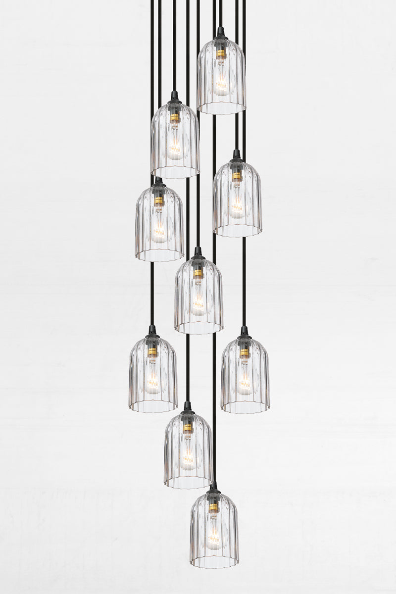 Nine fluted clear glass shades, paired with a black circular ceiling rose and cords. 
