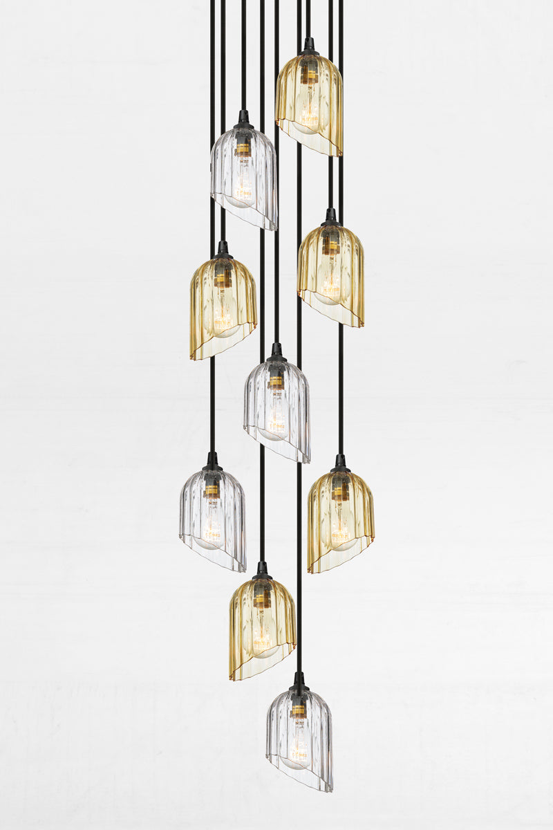 Nine fluted glass shades with an angled cut detail in amber and clear, paired with a black circular ceiling rose and cords. 