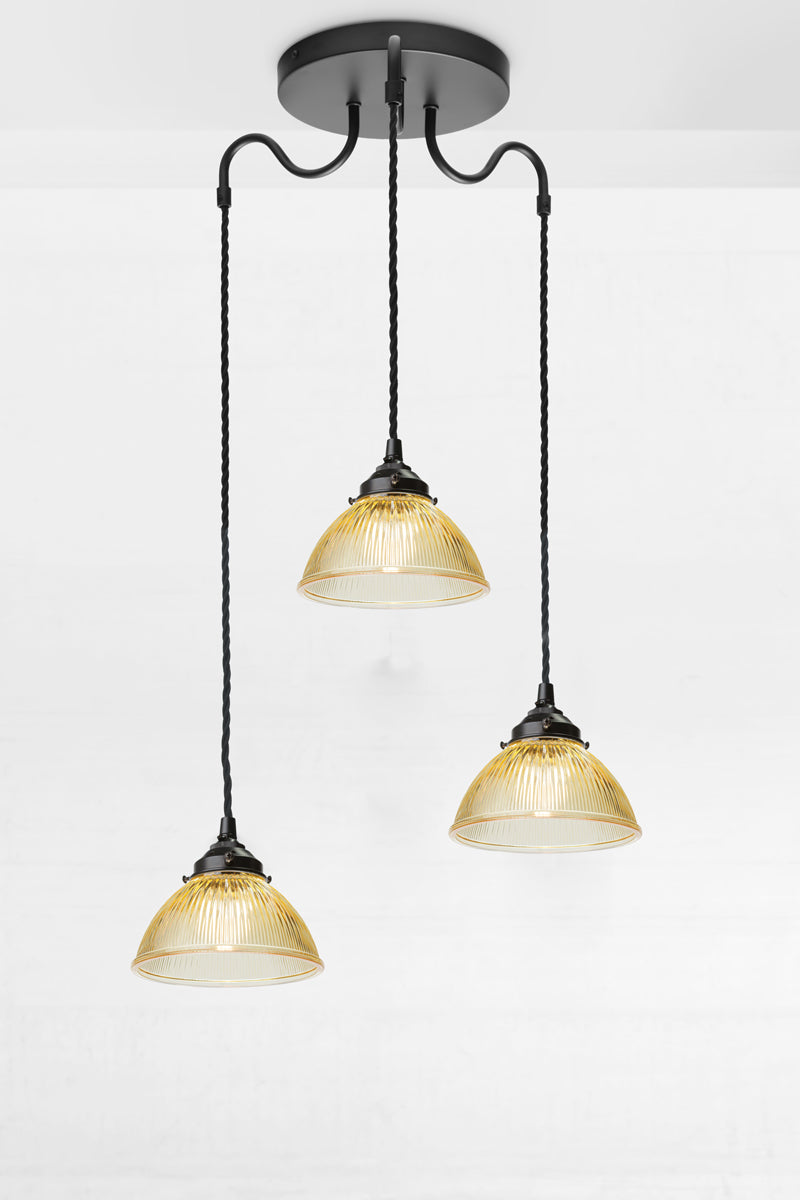 Black triple arm gooseneck pendant light with twisted cloth cords and three small amber glass shades. 