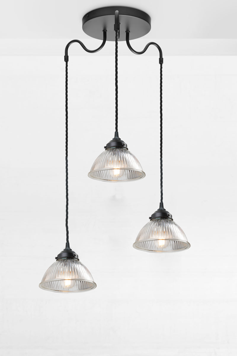 Black triple arm gooseneck pendant light with twisted cloth cords and three small clear glass shades. 