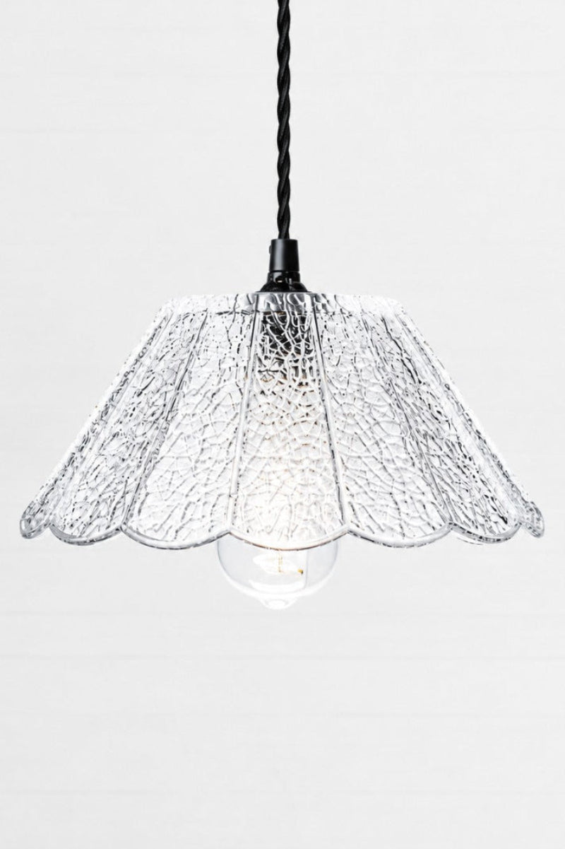 Straight on view of the clear glass shade with a crackle detailing, paired with black twisted cord. 
