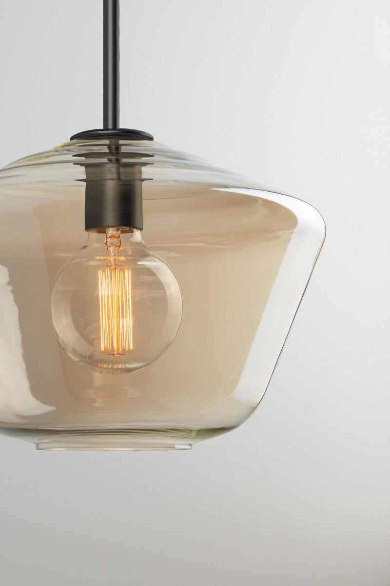 Close-up of Lugano champagne glass pendant shade A with angular profile, black lampholder and illuminated filament bulb.