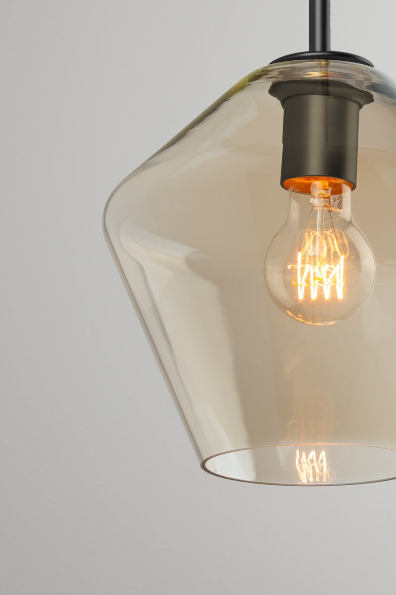 Close-up of rounded Lugano champagne glass pendant shade B with black lampholder and exposed filament bulb.