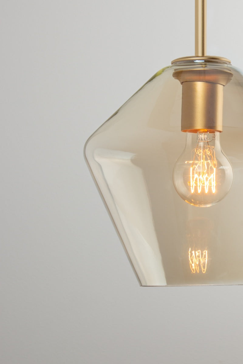 Lugano champagne glass pendant shade B with rounded sculptural profile, gold/brass lampholder and exposed filament bulb.