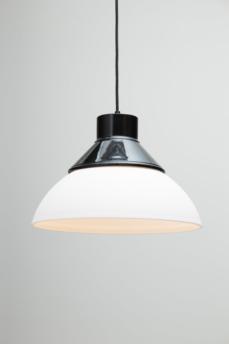 A modern pendant light with a white dome-shaped shade, a black top collar/ shade cover, and a black hanging cord. Homestead Foundry Pendant Light 