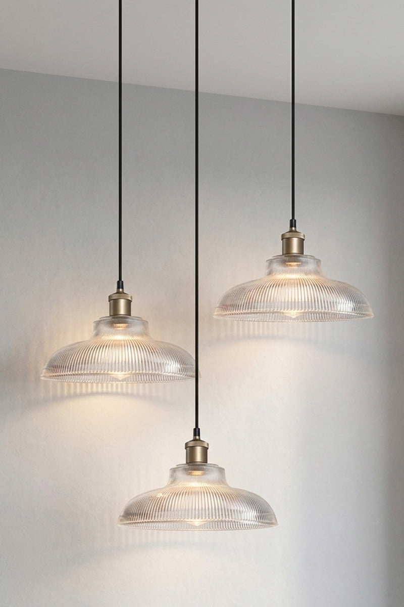 Three pendant light fixtures with ribbed clear glass shades on a multi drop light