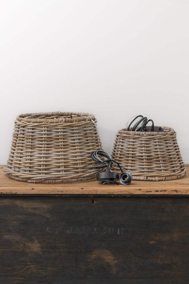 Two basket style pendant lights in a small and lard uninsalled on a timber bench. 