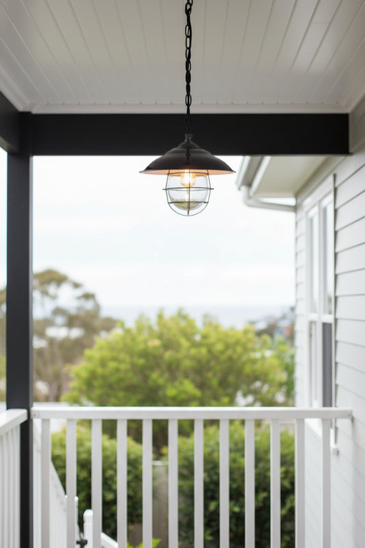 Porch fixture: our Engine Room Hanging Light hanging from a ceiling on a porch with a view of trees.