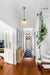  Two opal Auberge schoolhouse pendant light hanging in a white walled entrance hall, with timber floors. 