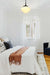 Opal Auberge schoolhouse pendant light hanging on a black chain and gallery in a bright bedroom.