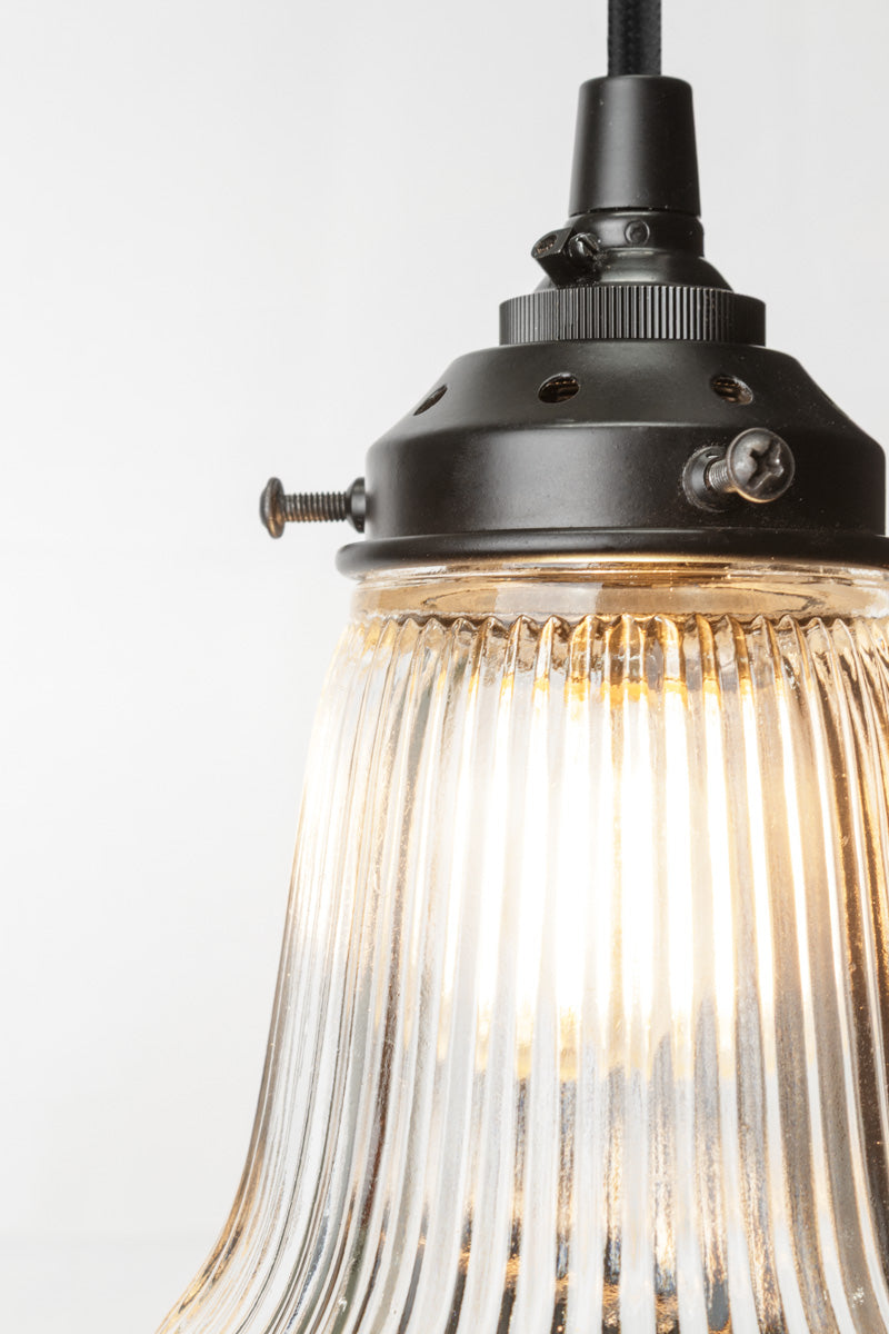 Close up of the ribbed clear glass pendant light with black hardware and cord. 