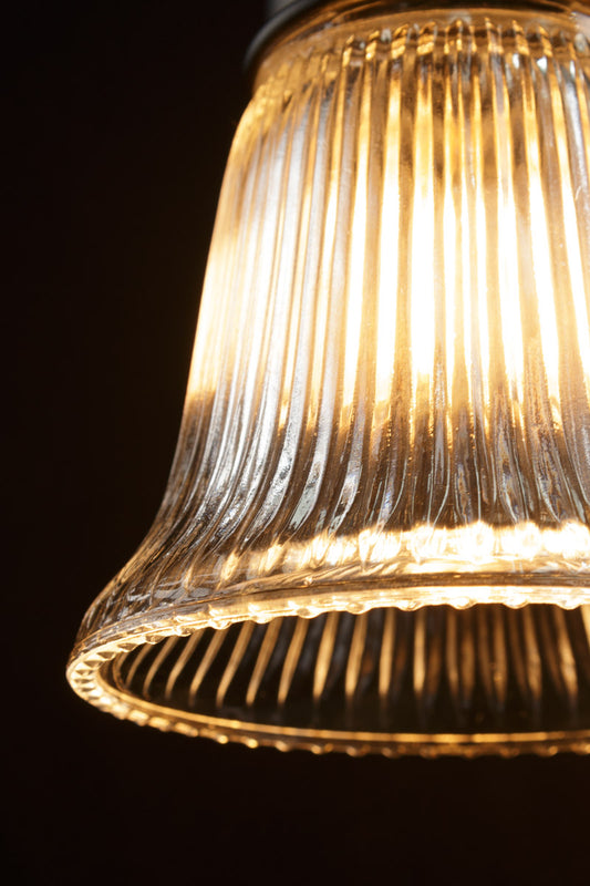 Close up of the ribbed clear glass pendant light in a dark room.