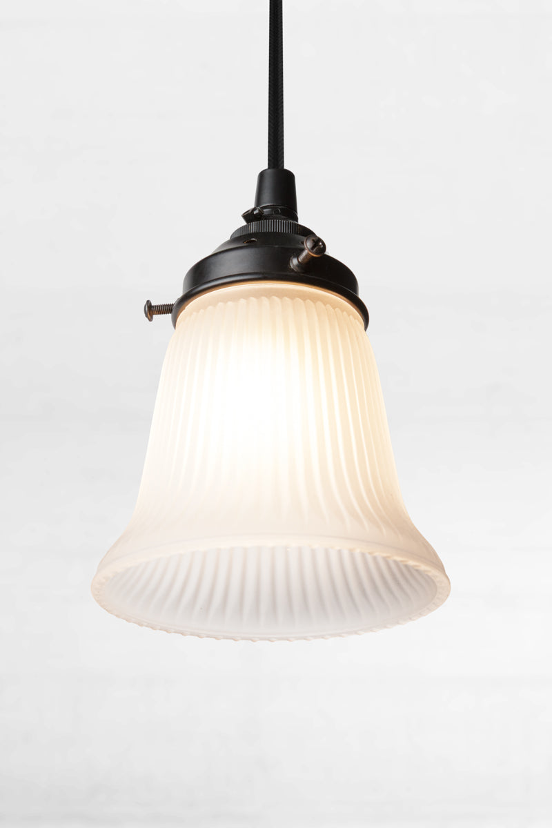 Small holophane opal glass shade on black hardeware with black cord and light on. 