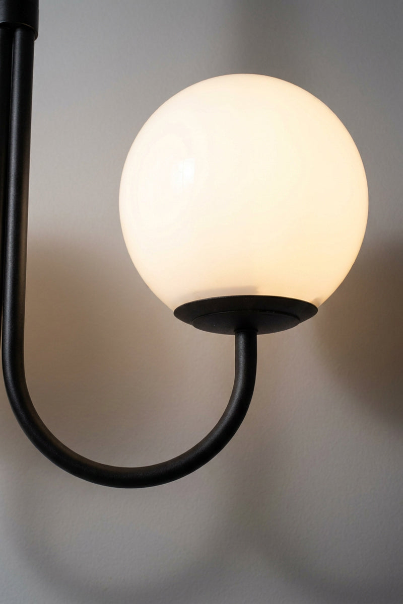 Side view of the Bonnie Glass Double Chandelier showing an opal glass globe mounted on a curved black arm