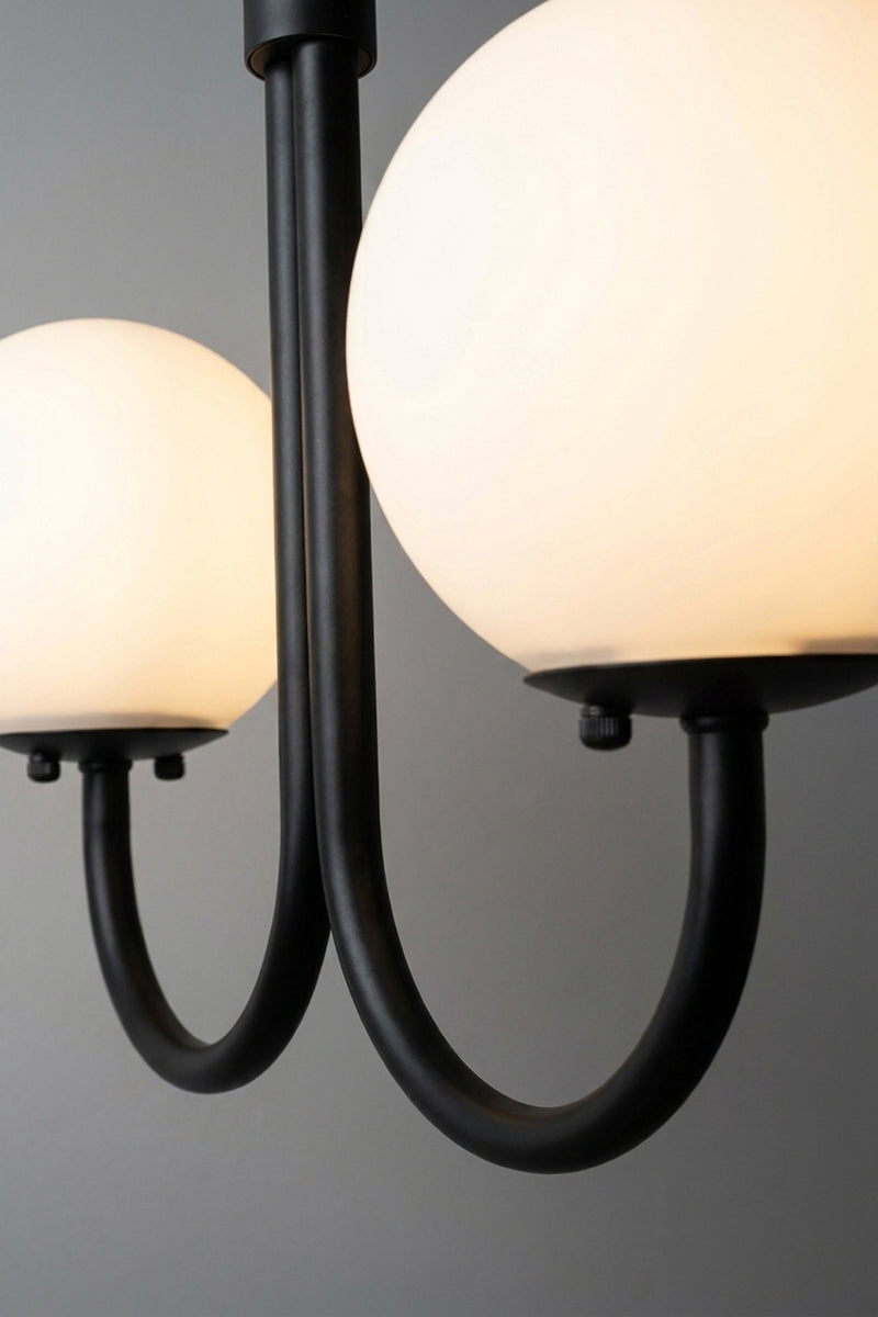 Close-up of illuminated opal glass globes and curved black metal arms on the Bonnie Double Chandelier