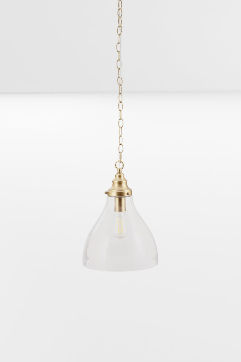 Small clear glass pendant with satin brass metalware and pictured with a clear teardrop bulb. 