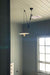 A black umbrella pendant hanging via a pully system in a light filled room. 