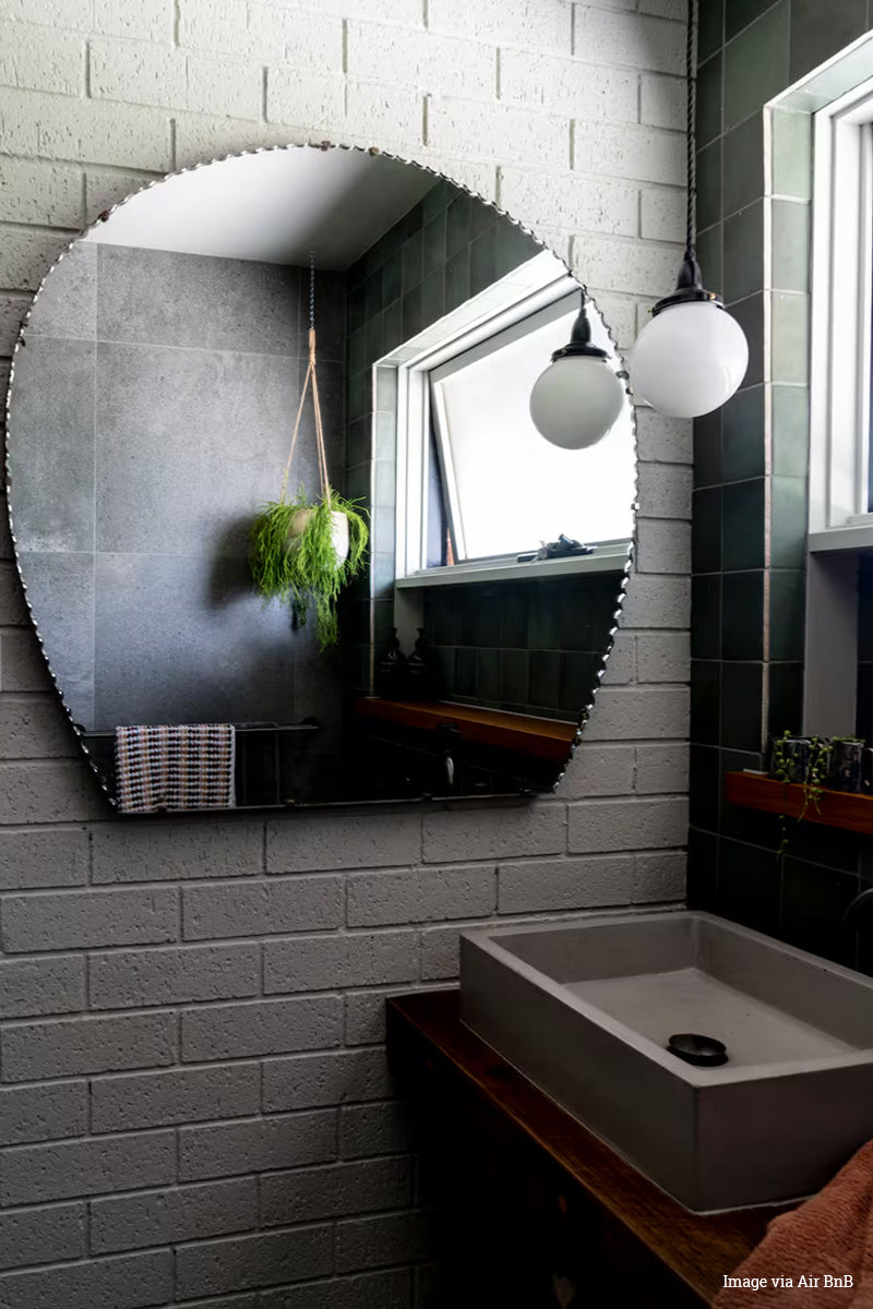 Black and Bright property, image via Air BNB. Opal glass ball shade with a black pendant cord as a vanity light. 