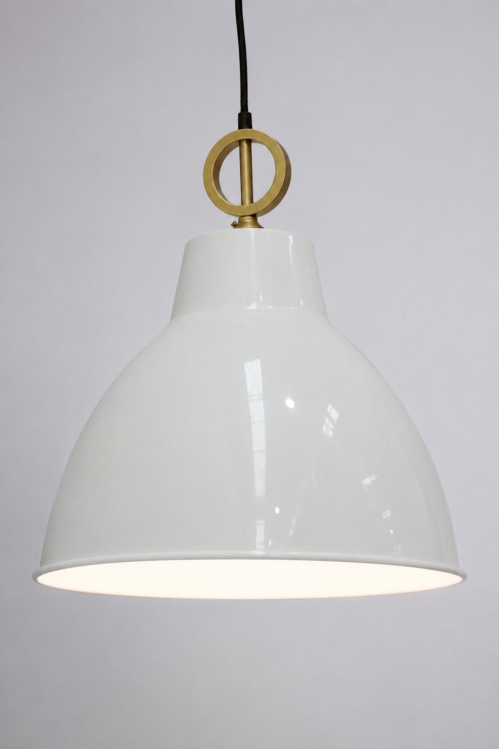 White painted steel shade on a black pendant cord with gold/brass circular mental detailing. 