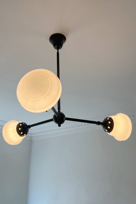 Colton Schoolhouse Chandelier illuminated in black finish with warm glowing schoolhouse glass shades