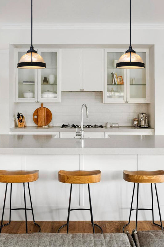Two clear ribbed glass dome shades with black metalware in a clean cut kitchen.
