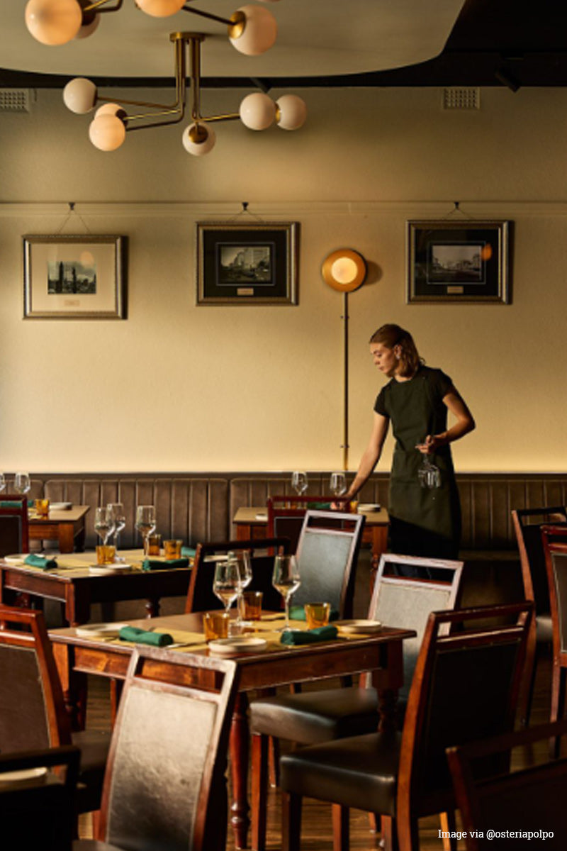 Image via @osteriapalpa Vintage feelinging dining space with waitress and opal glass/ gold multi lights. 