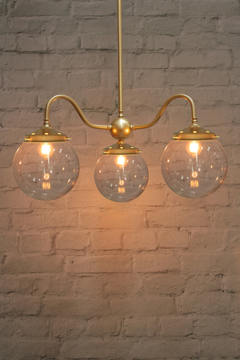 Medium, opal clear ball shades on a triple gold/brass gooseneck chandelier fixture. 