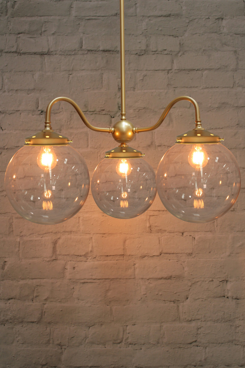 Large, opal clear ball shades on a triple gold/brass gooseneck chandelier fixture. 