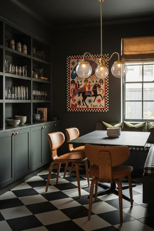 Brass three light pendant with clear glass globes on curved arms, hanging over a dining table in a dark green dining nook