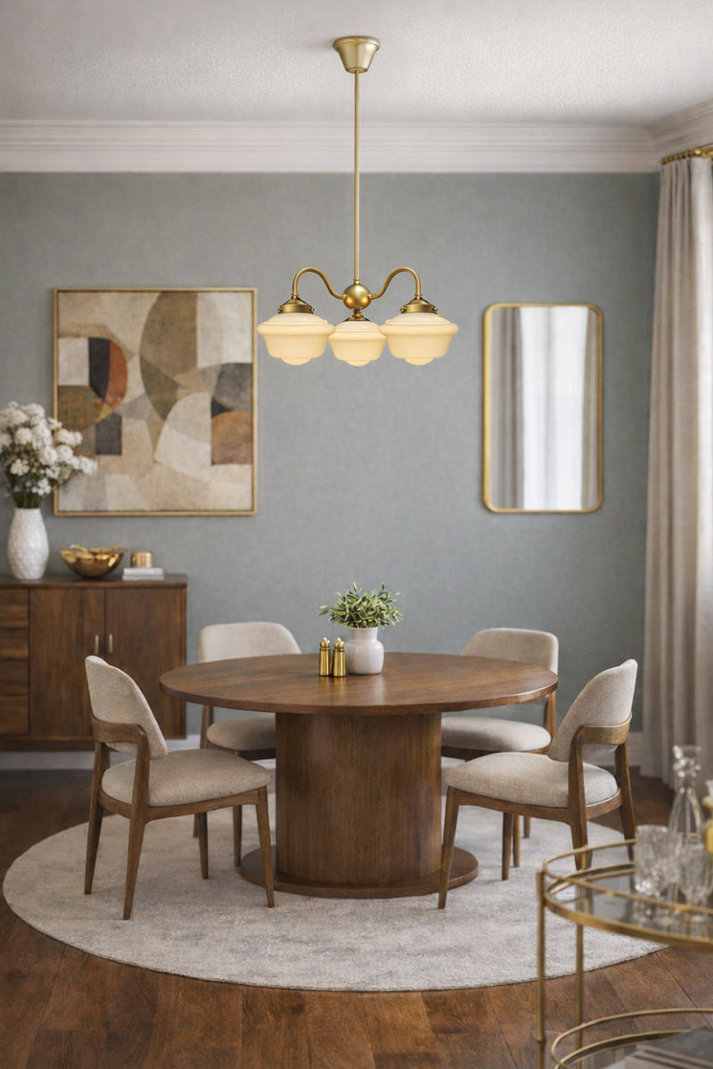 Gold/brass three arm gooseneck changalier with schoolhouse shades over a dining space. 