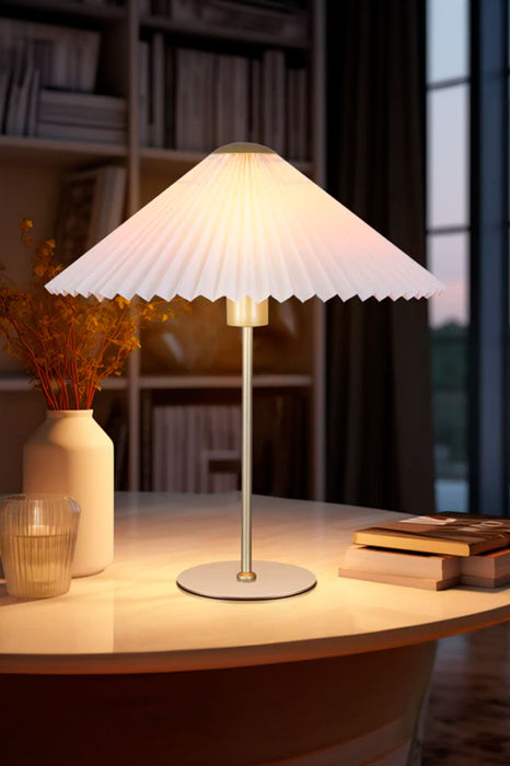 Table lamp with a pleated shade positioned on a desk
