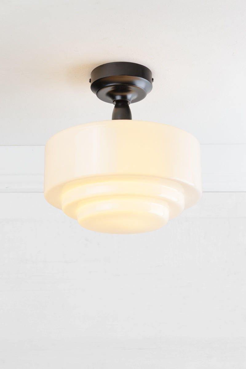Opal glass shade with stepped silluetteand a black batten holder. 