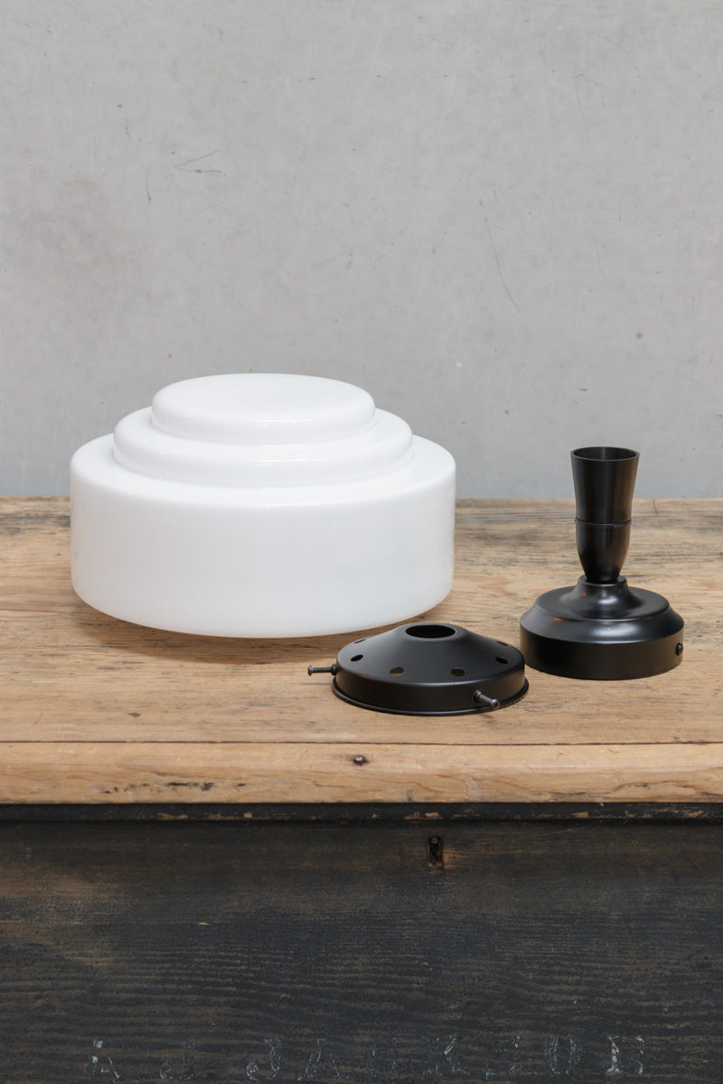 Unistalled opal glass shade with stepped silluette and a black gallery and batten holder. 