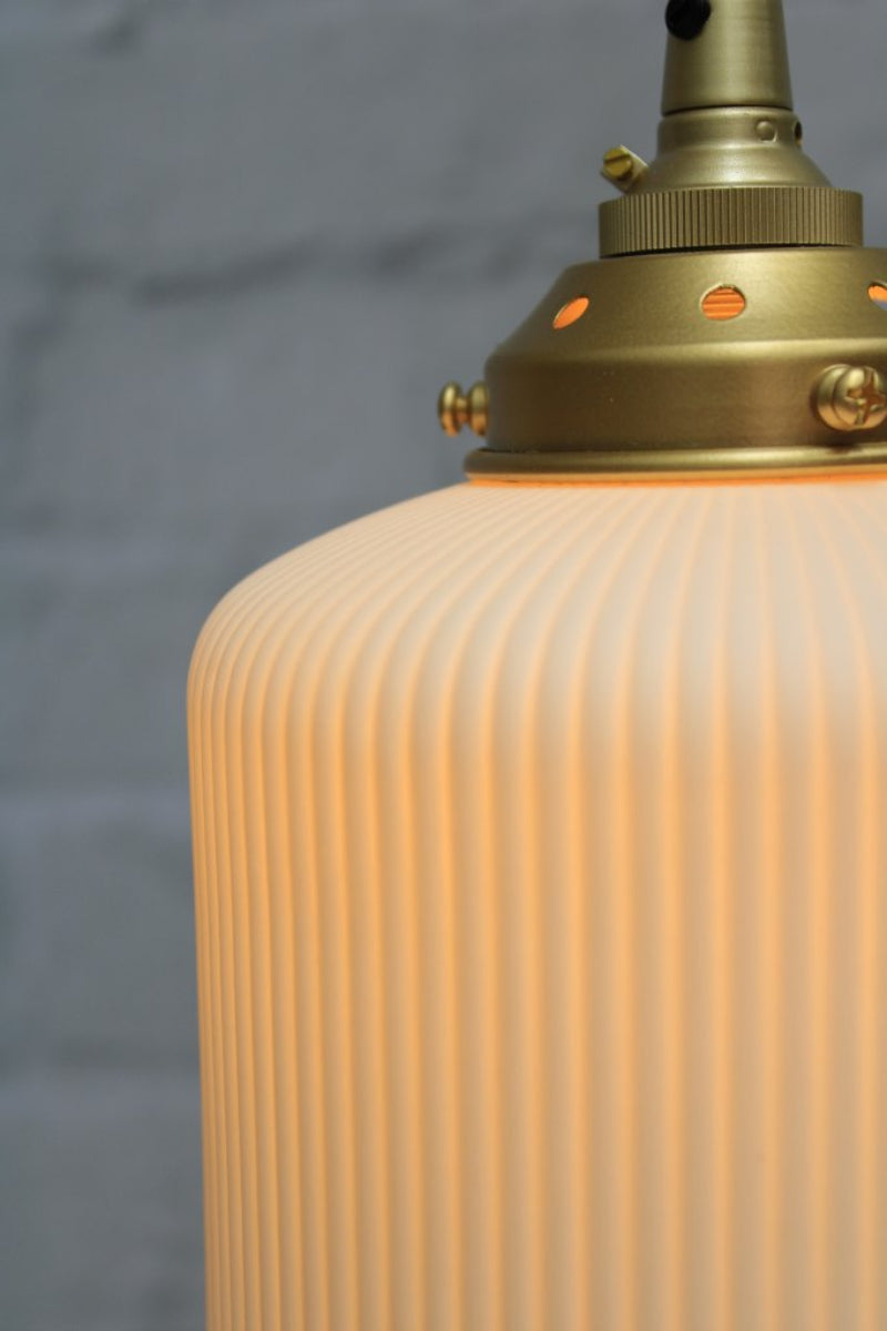 Close up of the matt white ribbed ceramic shade and gold/brass hardware. 