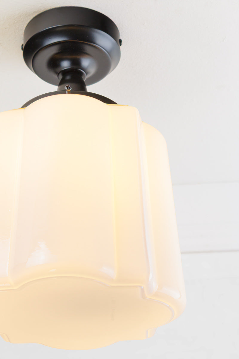 Close up of the opal curved glass shade with distinctive deco scalloped detailing, paired with a white batten holder and gallery