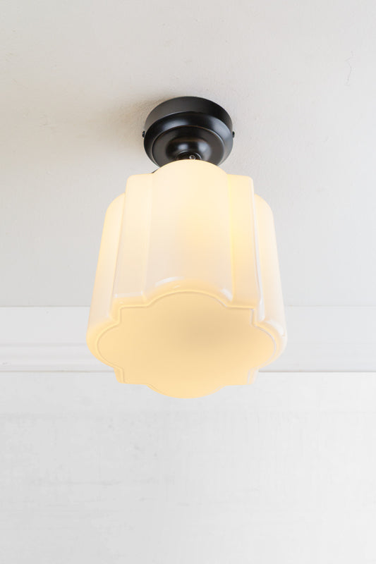 Opal curved glass shade with distinctive deco scalloped detailing and flat bottom, paired with a black batten holder and gallery