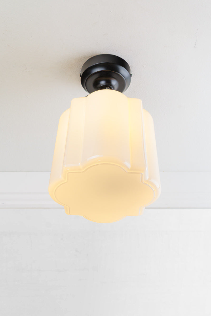 Opal curved glass shade with distinctive deco scalloped detailing and flat bottom, paired with a black batten holder and gallery