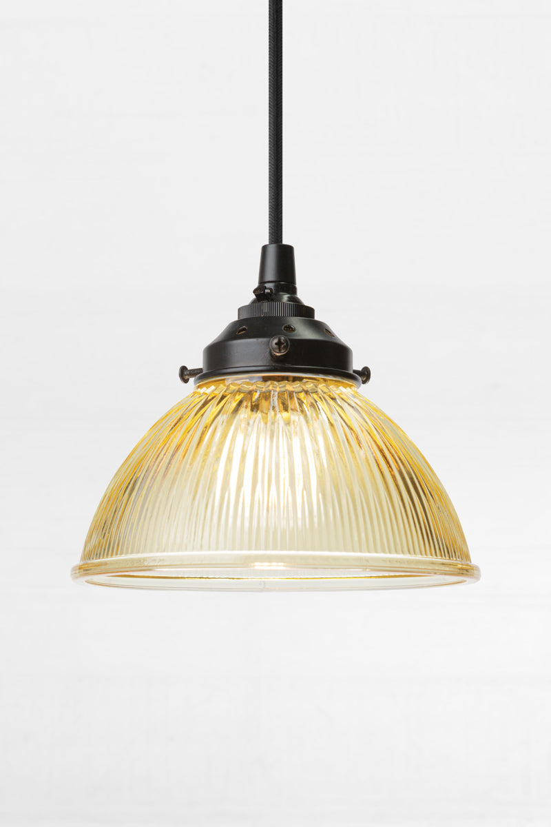 Amber glass shade with ribbed detailing on a black pendand cord and hardware