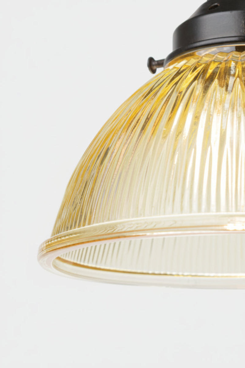 Close up of the Amber glass shade with reeded detailing on a black gallery