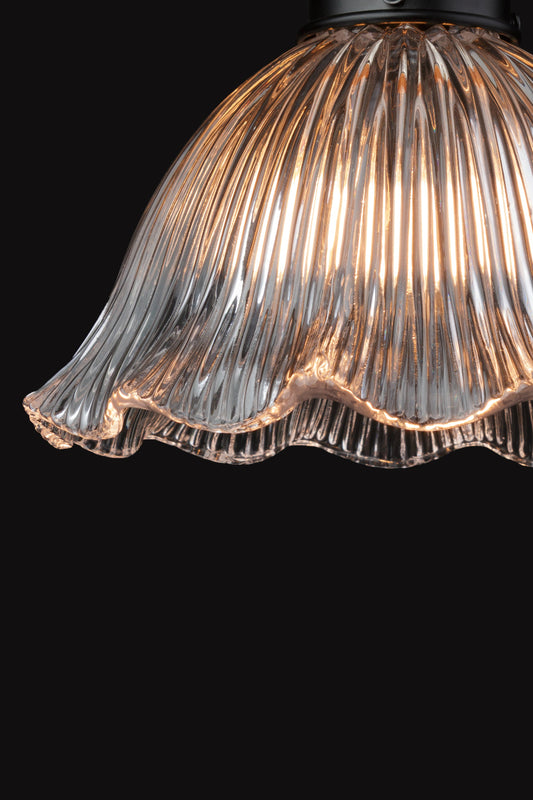 Close up of the reeded detailing and frilled edge of this clear glass shade. 