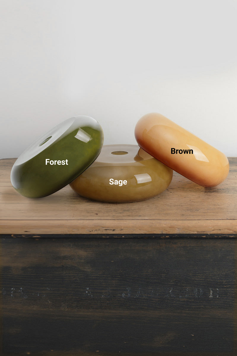 Three Avoca glossy glass shades, labeled with their finish colour and placed on a timber bench. 