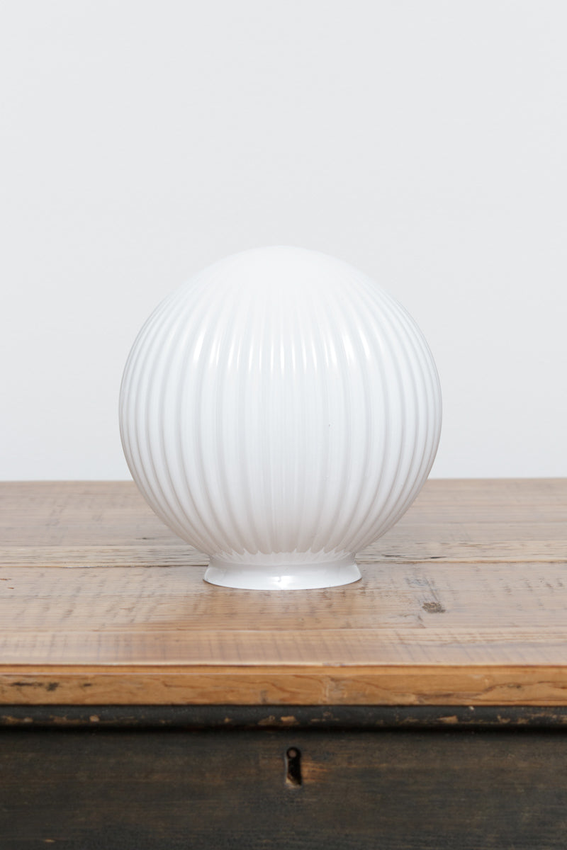 Glass ball shade in opal with reeded detailing on a timber bench. 