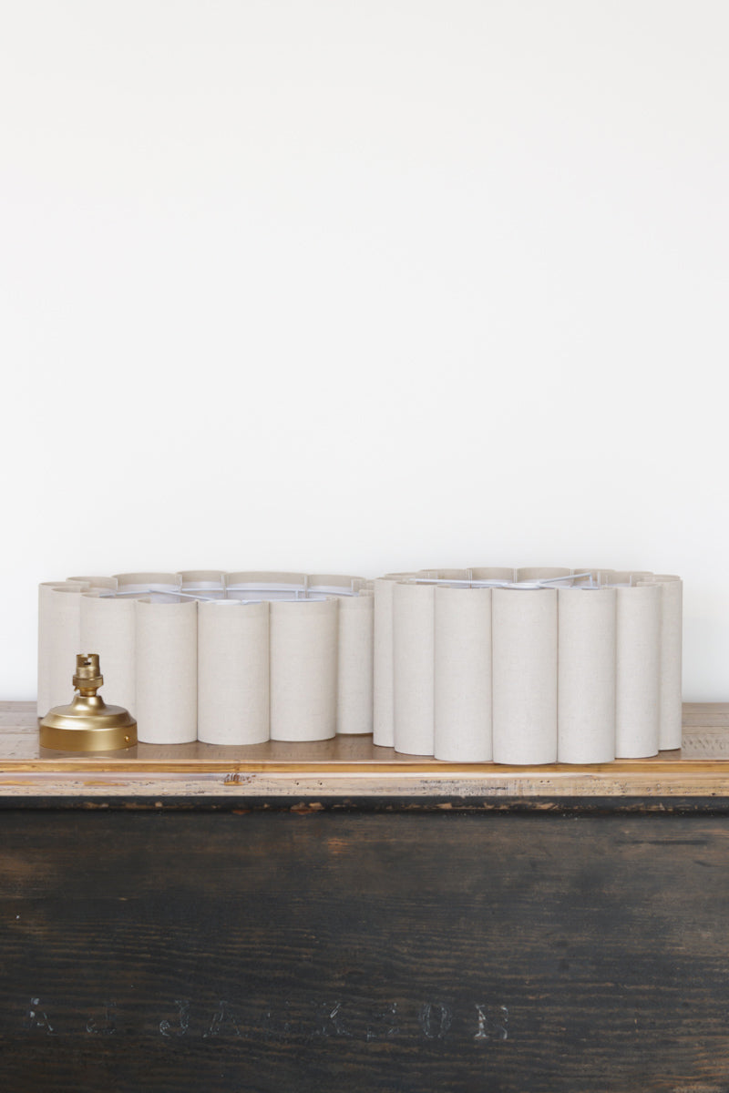 Uninstalled neutral toned scalloped shades with gold/brass batten holder. 
