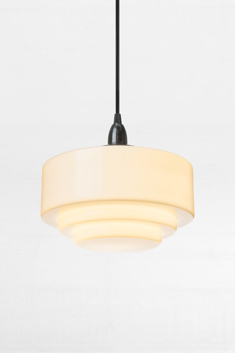 Stepped detailing of the opal schoolhouse shade with stepped detailing and a black endant cord. 
