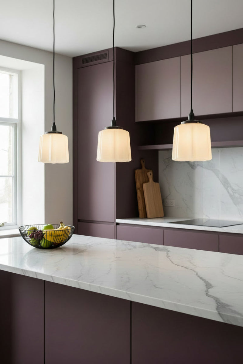 Three opal glass shades with a deco design influence in a kitchen with marble benches and plum tones. 