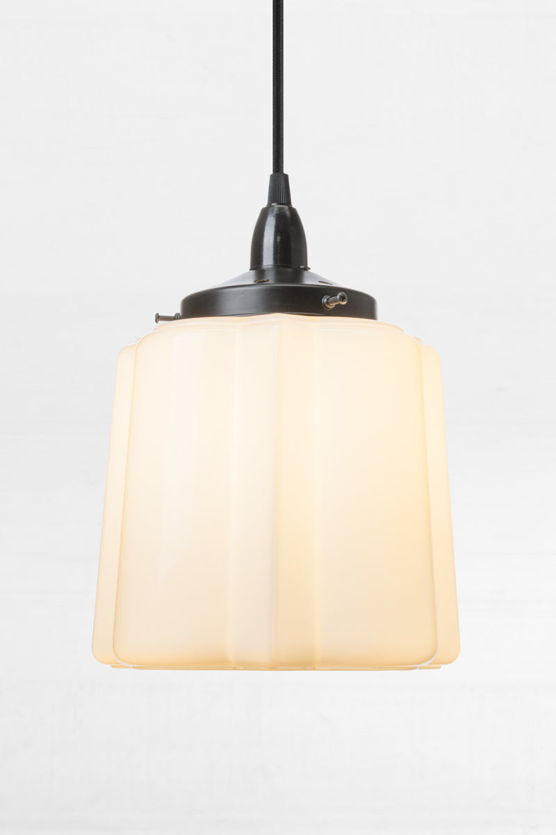 Straight on view of the Opal glass unique deco shade on a black cord and lampholder. 