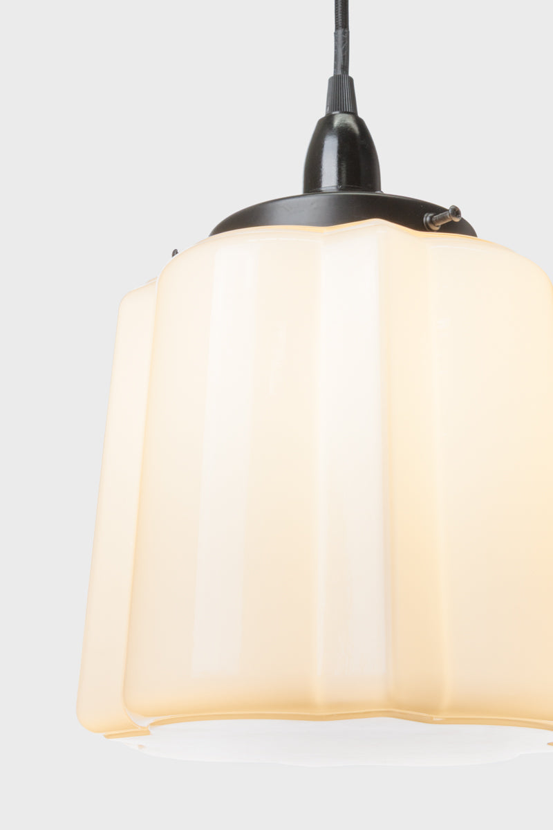 Close up view of the opal glass unique deco shade on a black cord and lampholder