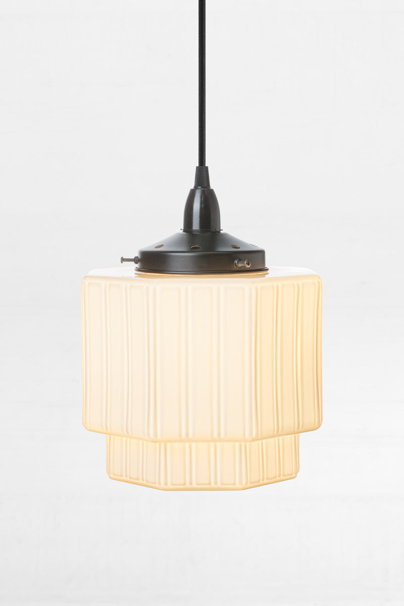 Art Deco inspired opal shade with step detailing paired with a black pendant cord and gallery. 