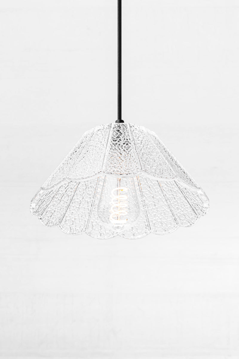 Clear crackle glass shade with scalloped edge on a black cloth pendant cord. 