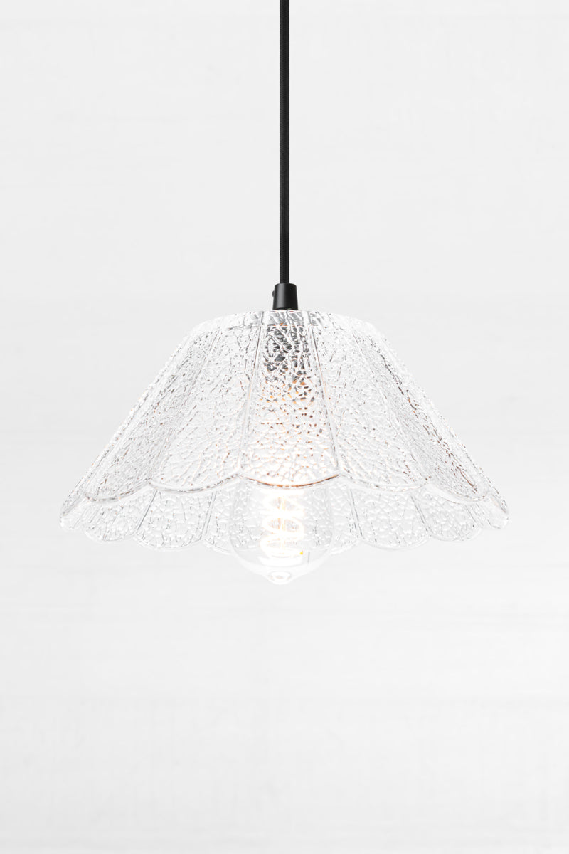 Clear crackle glass shade with scalloped edge on a black cloth pendant cord. 